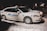 Two white taxis are parked on a snowy street at night. The vehicles have the name 'Bluebird Stephenville' written on the sides in blue lettering, with the numbers 9 and 1 visible. The scene is dimly lit, with a few lights visible in the background.