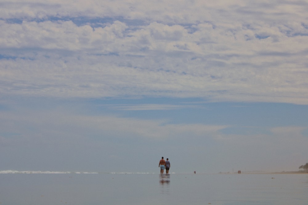 two person walking body of water