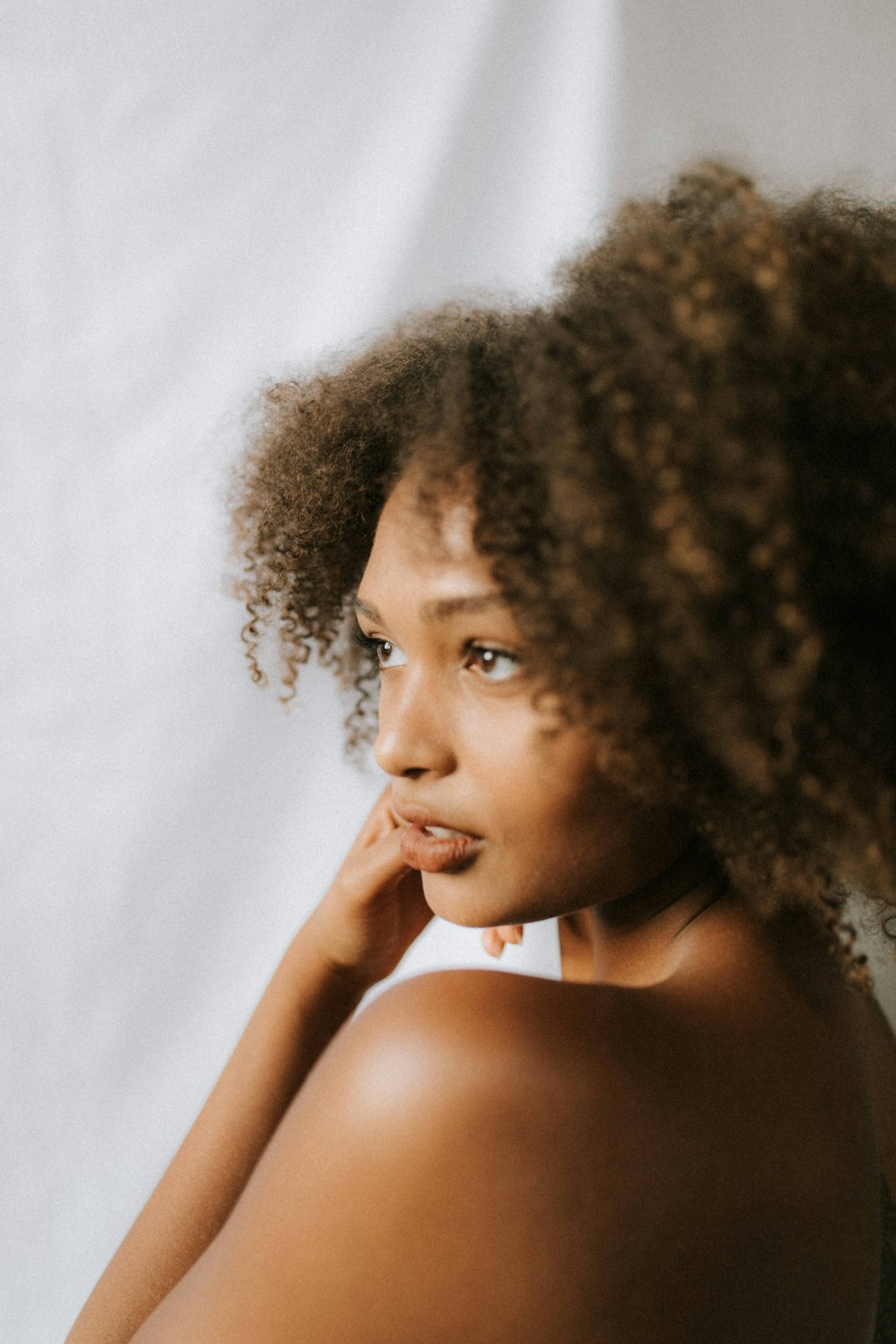 curly-haired topless woman glancing her left side