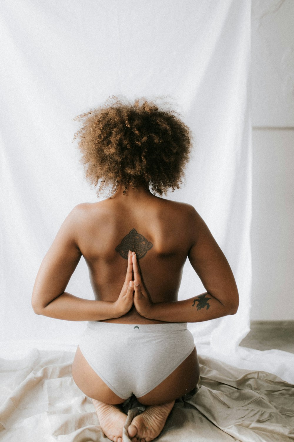 woman kneeling with both hands on her back doing praying gesture