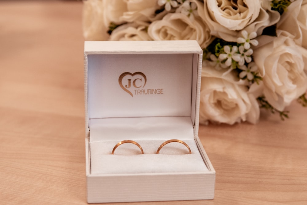 gold-colored JC earrings in box