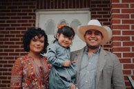 woman, toddler girl, and man smiling and looking at the camera