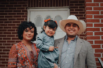 woman, toddler girl, and man smiling and looking at the camera