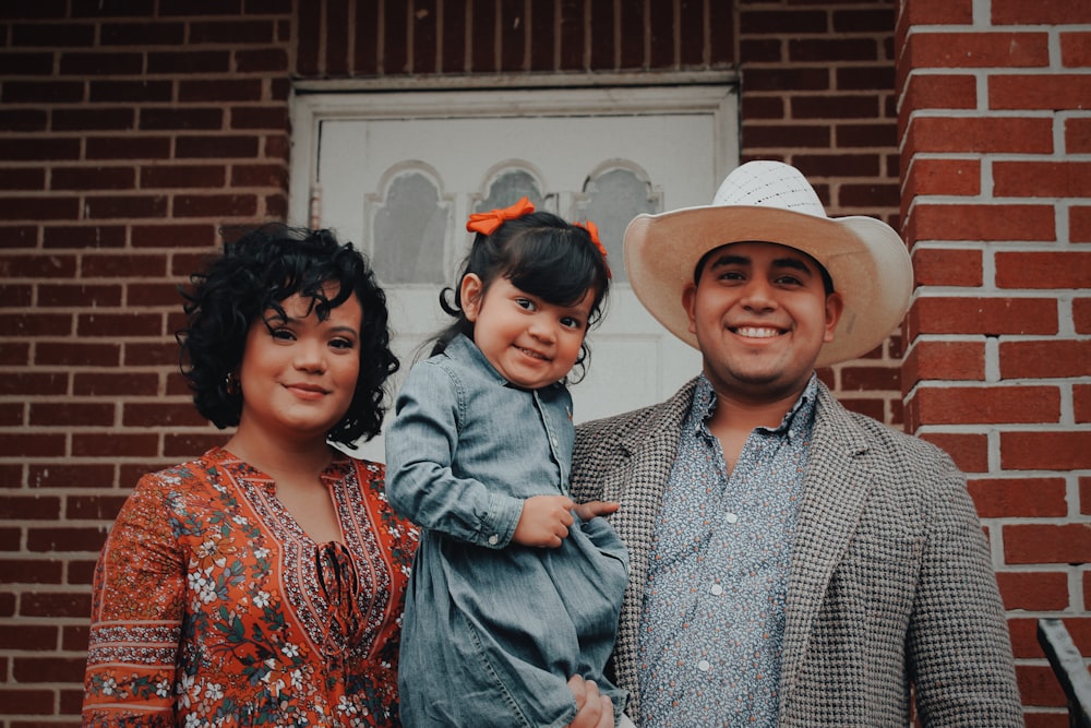 woman, toddler girl, and man smiling and looking at the camera