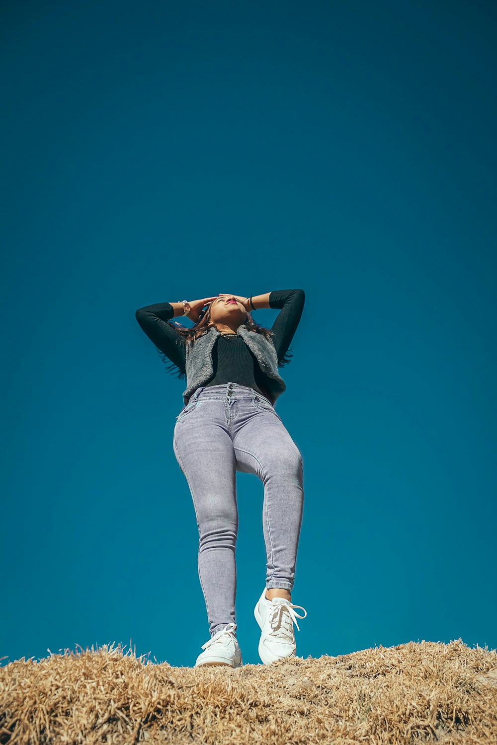 woman standing with both hands touching her head