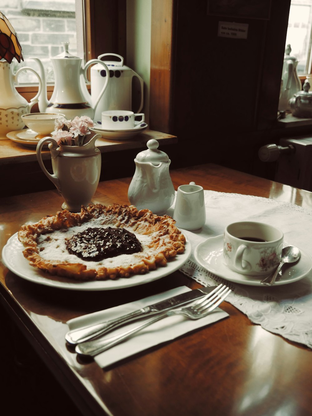 pie on plate beside knife, fork, and mug