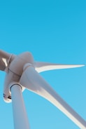 Close-up of wind turbines turning against a blue sky.