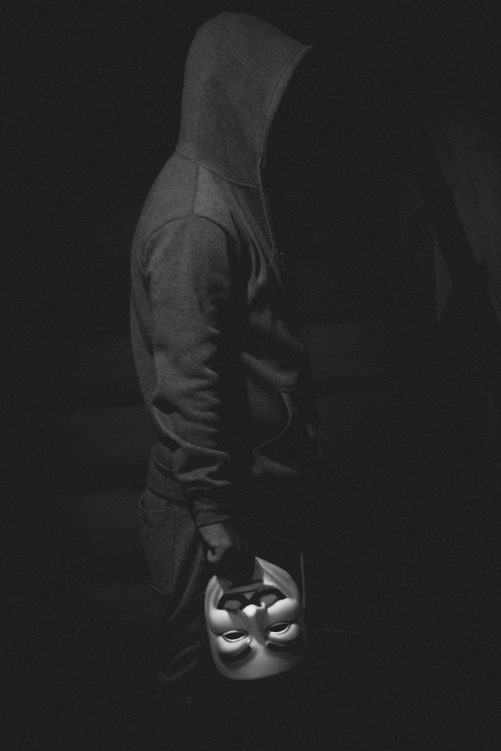 standing man holding Guy Fawkes mask