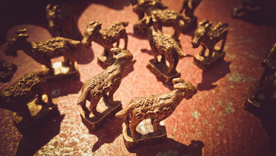 Elegant brass figurines arranged on a wooden shelf with natural sunlight.