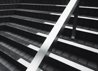 grayscale photography of stairs with a handrail during daytime