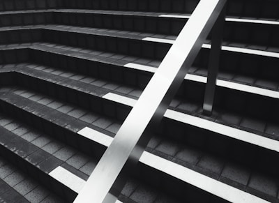 grayscale photography of stairs with a handrail during daytime