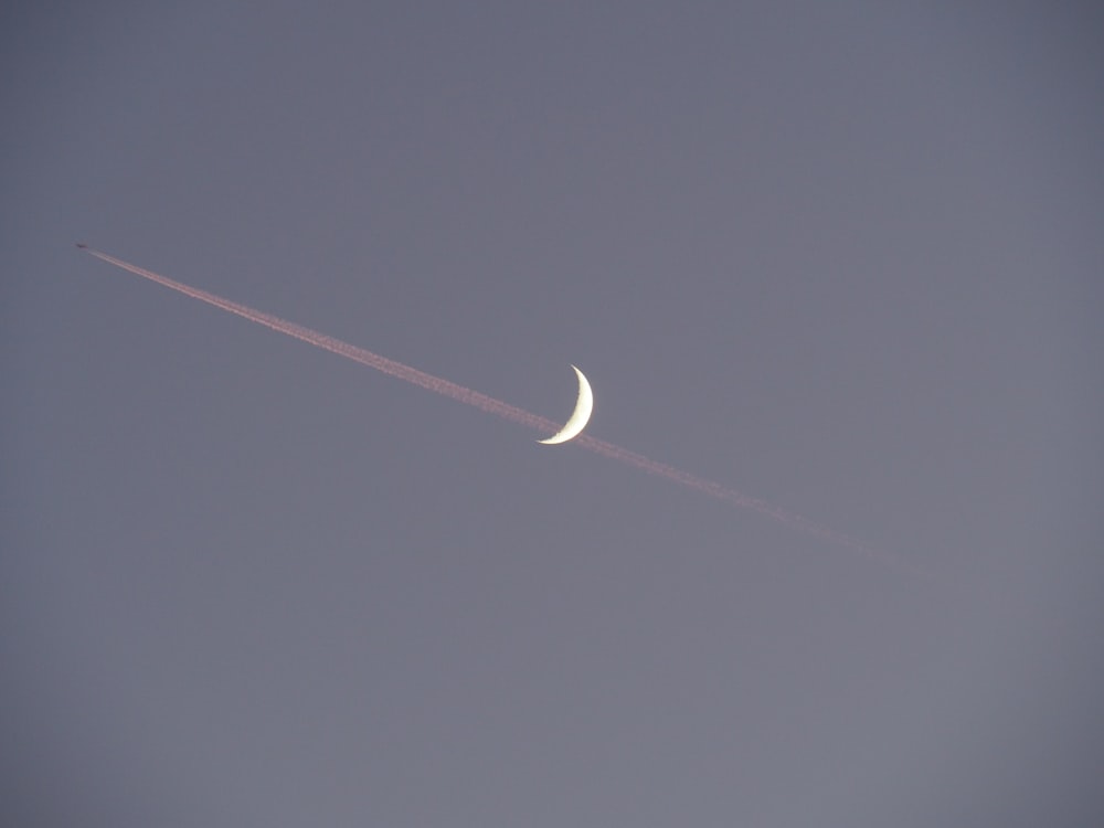 half moon and contrail during day