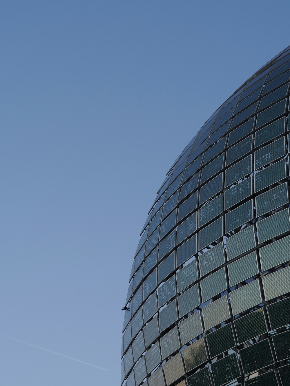 a plane flying in the sky near a building