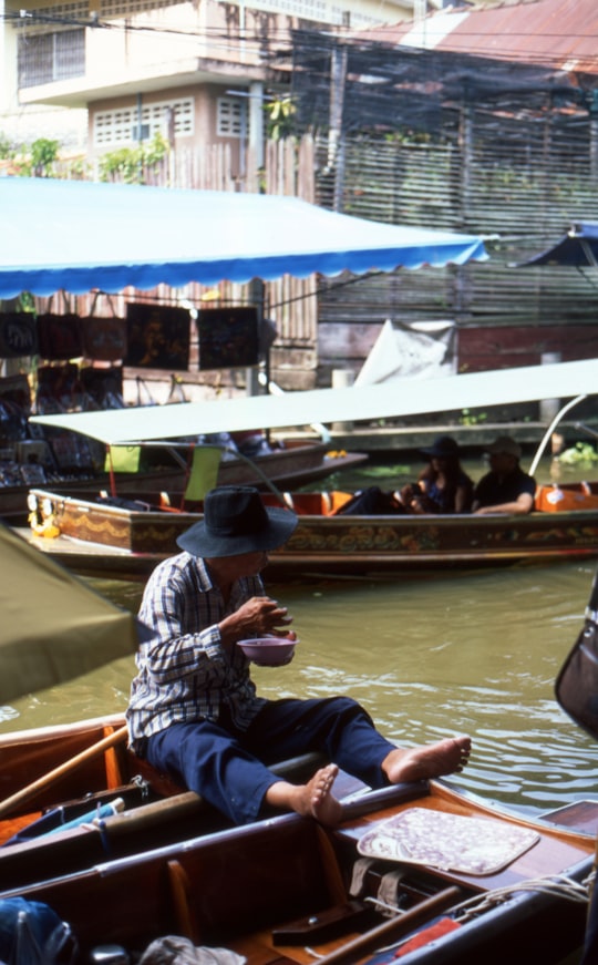 man sitting on boat in Damnoen Saduak Thailand