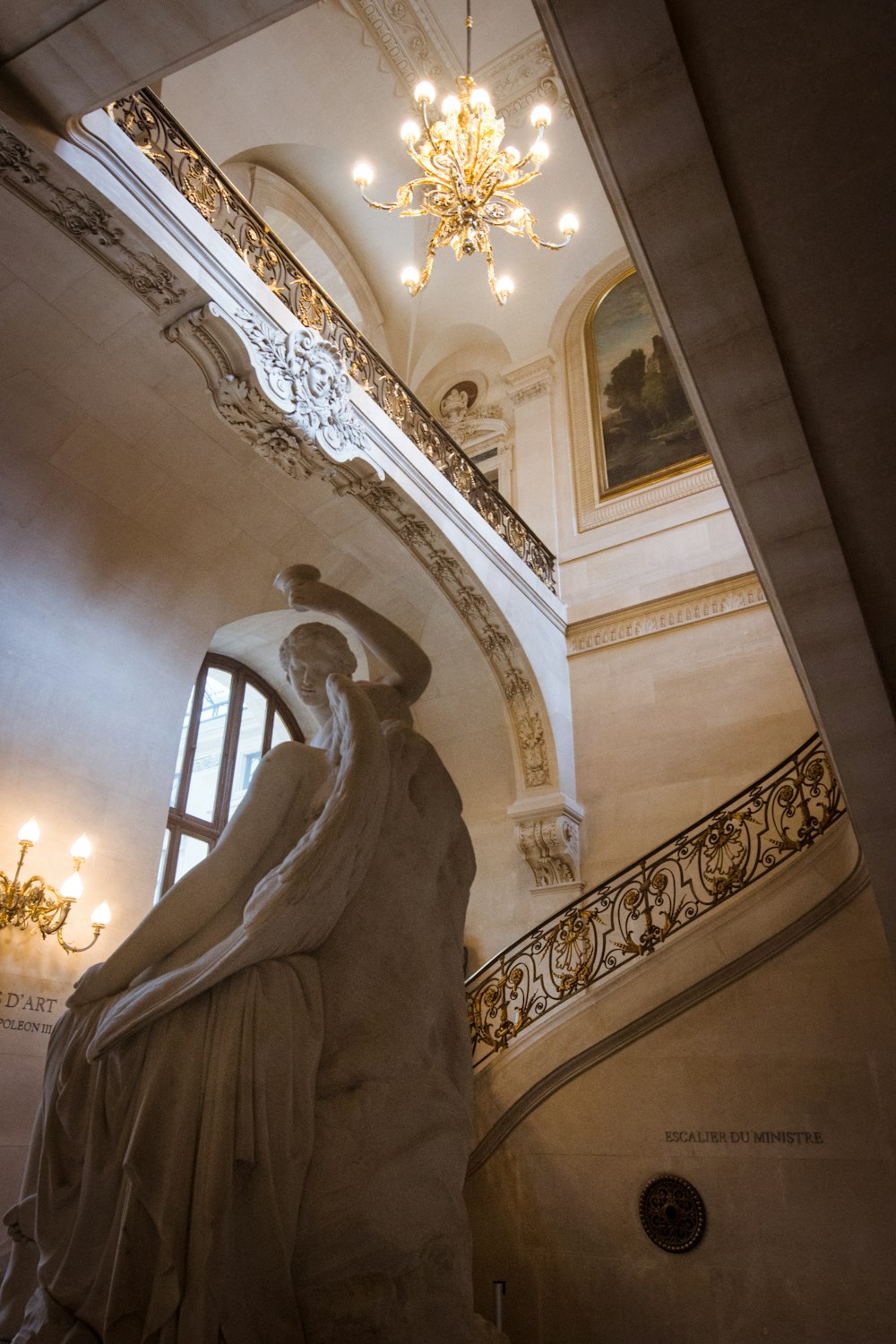 a statue of a woman in a room with a chandelier