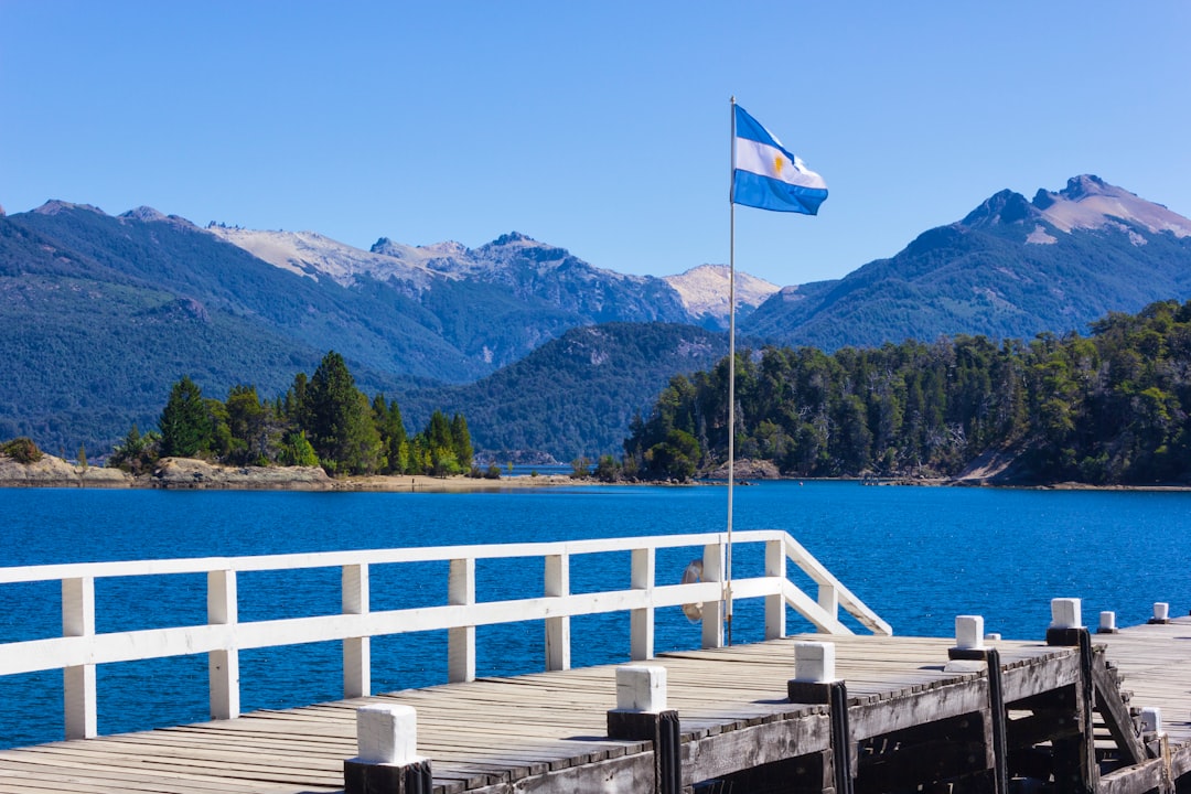 white and blue flag on wooden dock near body of water during daytime