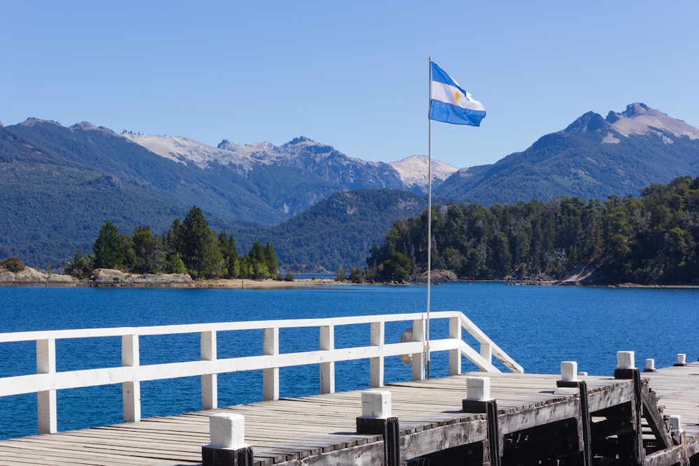 Bandiera bianca e blu sul molo di legno vicino allo specchio d'acqua durante il giorno