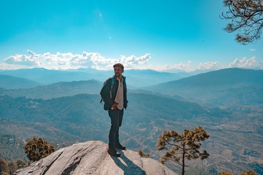 man standing on rocky edge of a mountain during day