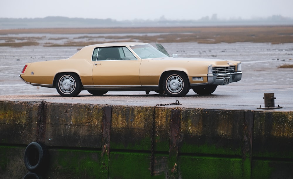 gold coupe parked at the pier