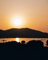 Sunset casting warm hues over the estuary with kayaks silhouetted against the sky.