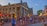 A bustling outdoor scene with numerous people walking or standing around a historic market building with columns. The building, called Quincy Market, has a classic architectural style. Red umbrellas and lights adorn an outdoor dining area where people are sitting. The street is paved with brick, adding a historic charm to the area. Signs for nearby businesses are visible, and trees and cityscape can be seen in the background.