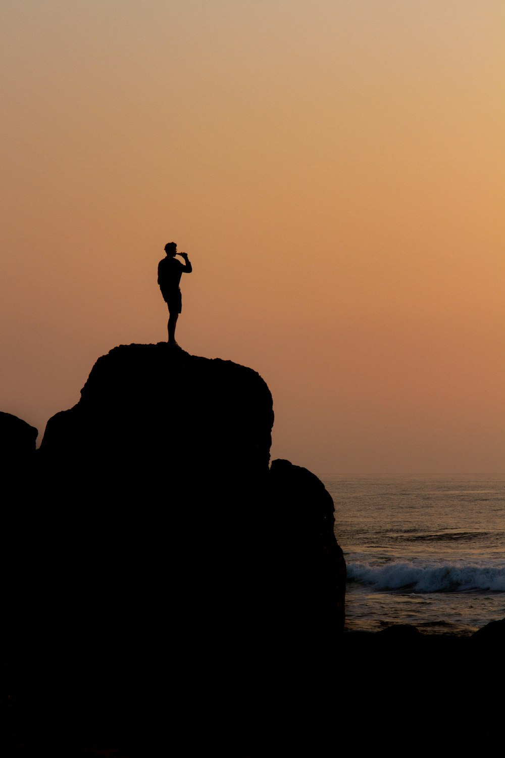 silhouette of person standing on cliff