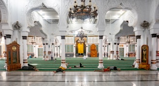 A team cleaning a large mosque interior with attention to detail.
