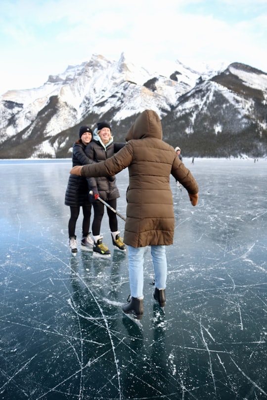 person in brown coat standing in front of couple in Lake Minnewanka Canada