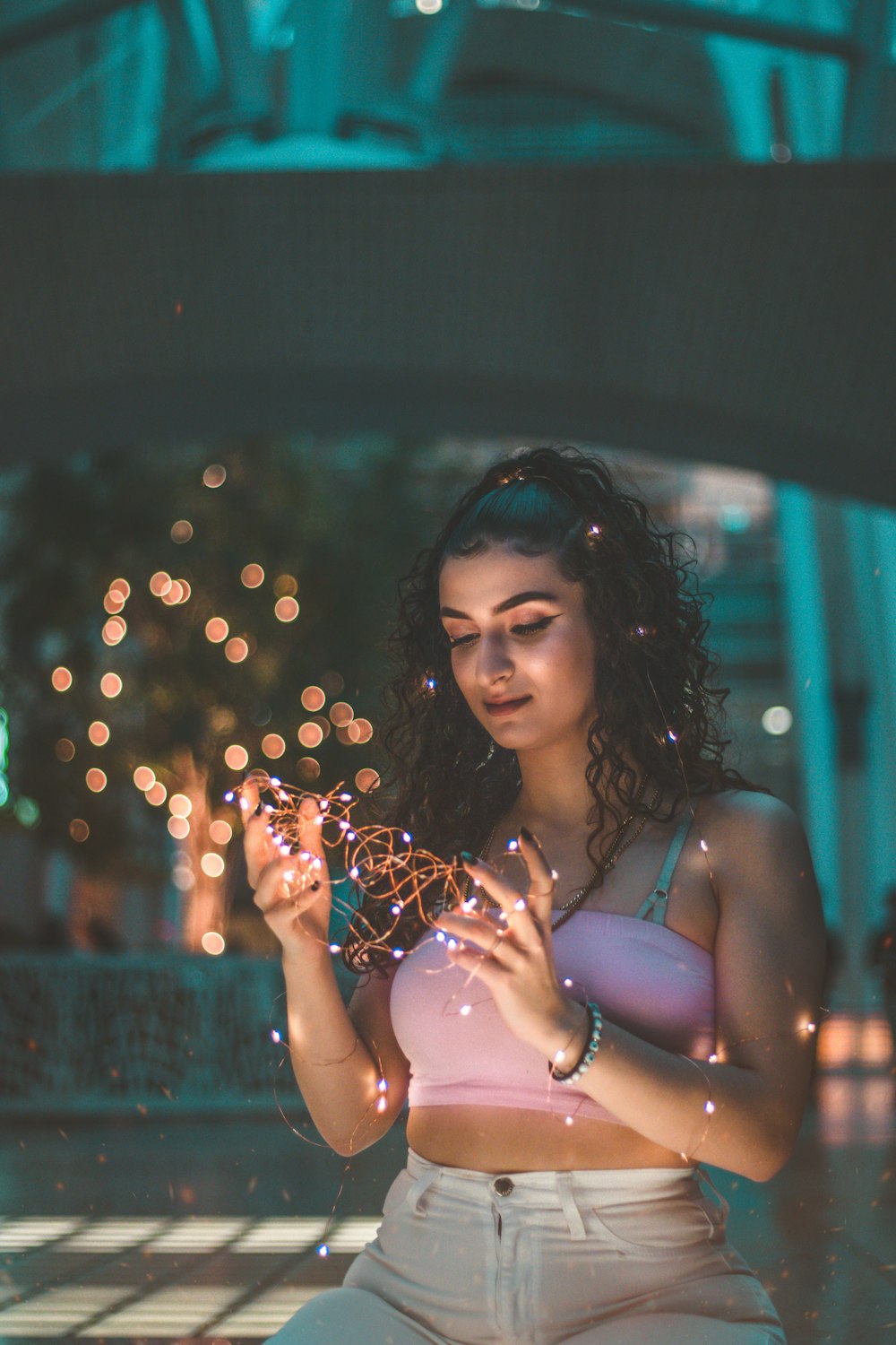 woman wearing pink crop top holding string light