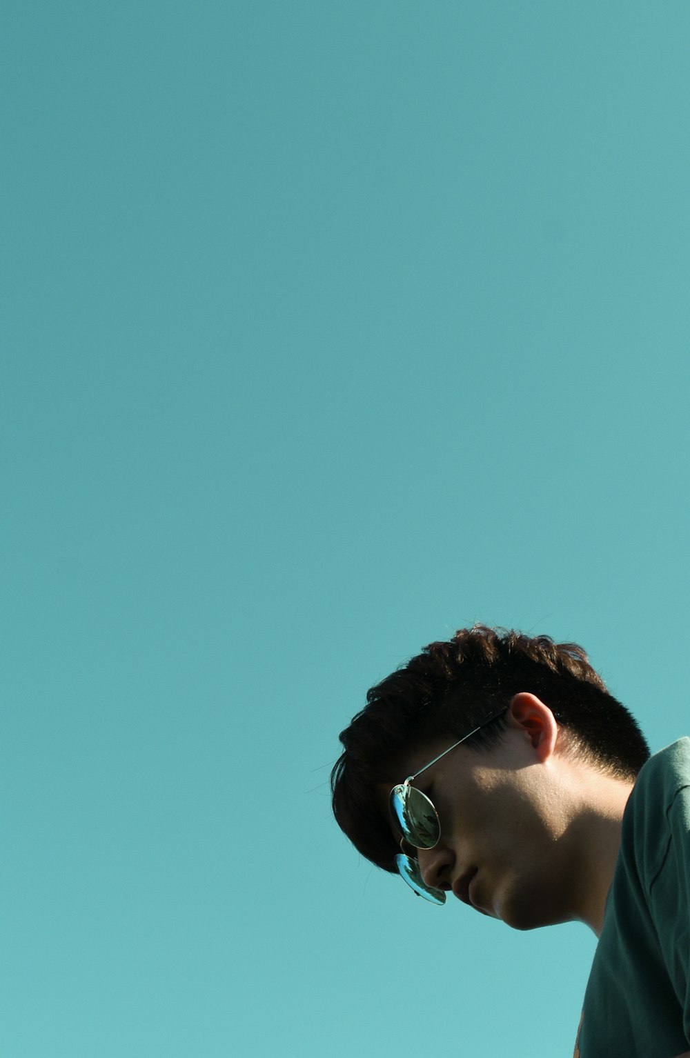 a man with sunglasses looking down at his cell phone