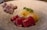 A dish featuring vibrant red tuna slices, complemented by a creamy-looking sauce and garnished with finely grated cheese or egg. Fresh green herbs add a touch of color and freshness. On the side, there appears to be a portion of shredded meat or fish.