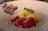 A dish featuring vibrant red tuna slices, complemented by a creamy-looking sauce and garnished with finely grated cheese or egg. Fresh green herbs add a touch of color and freshness. On the side, there appears to be a portion of shredded meat or fish.