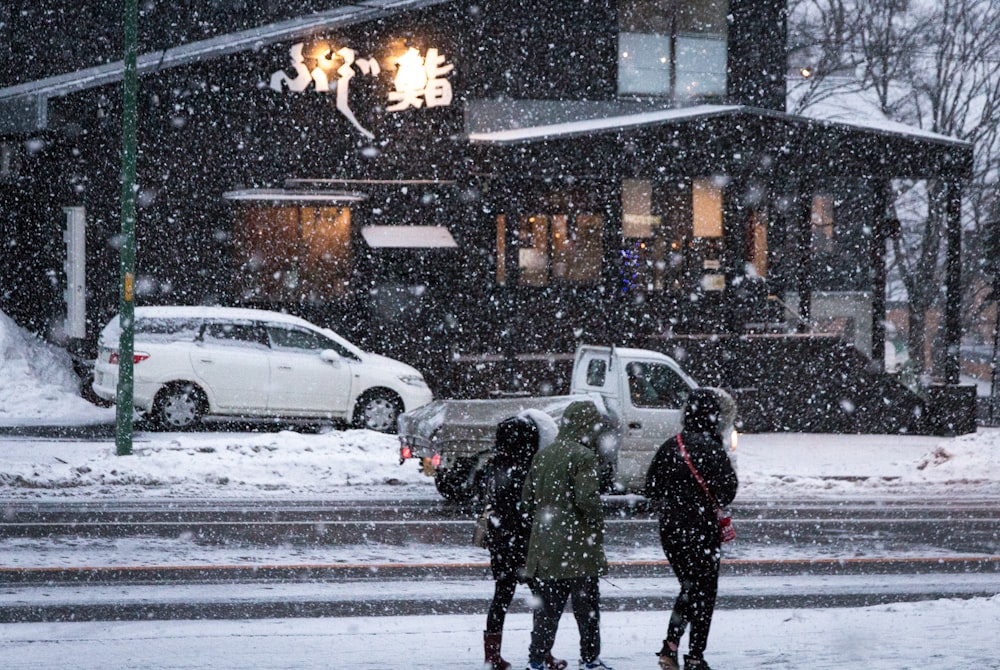 a group of people walking across a snow covered street