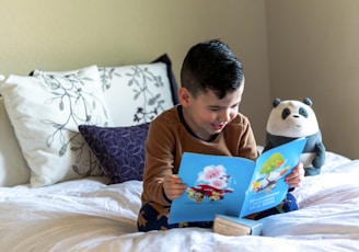 boy reading book on bed