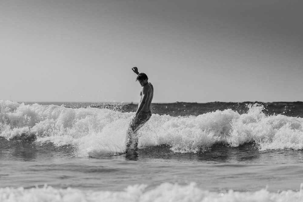 grayscale photography of man surfing in the beach