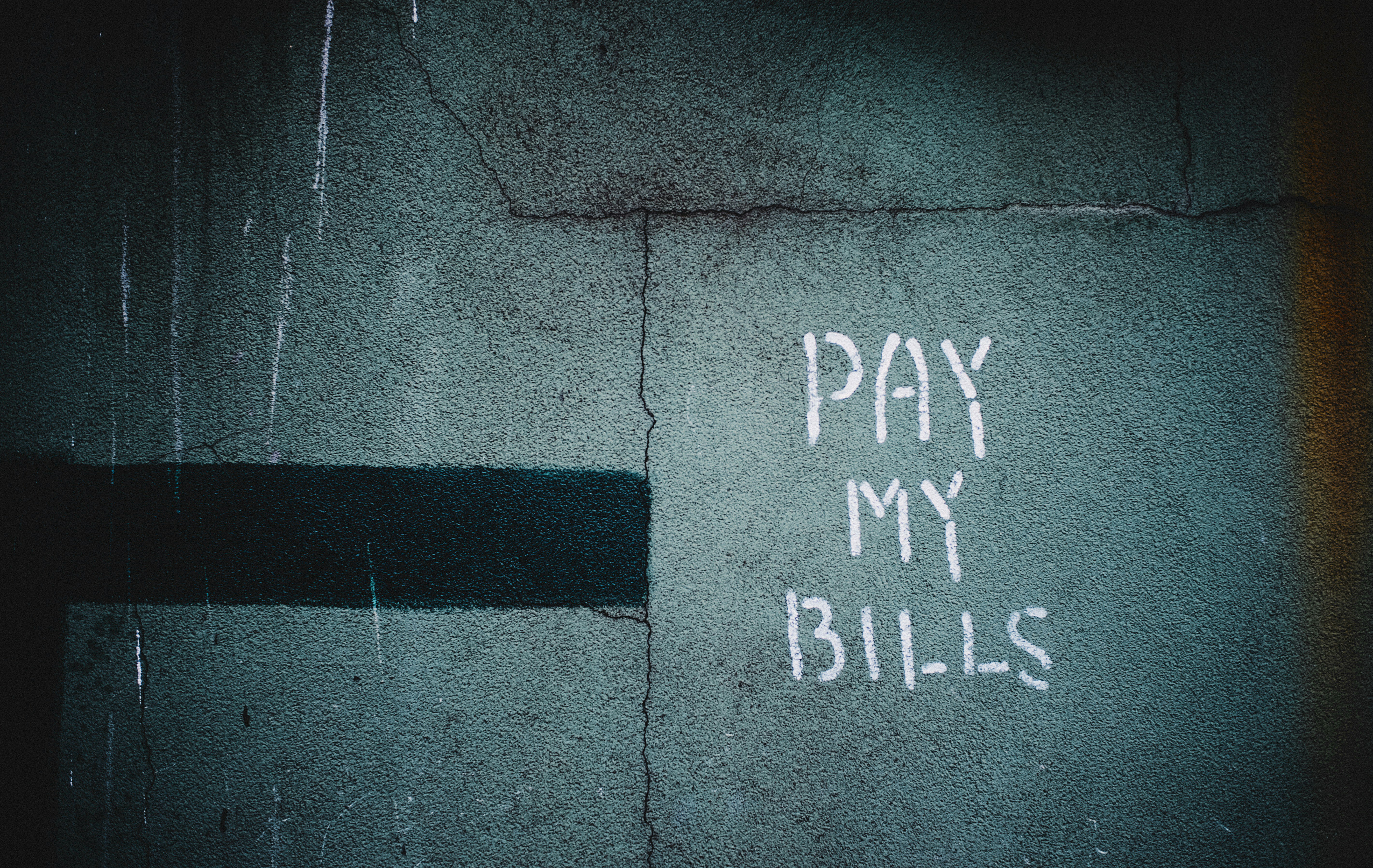 shallow focus photo of wall with pay my bills paint