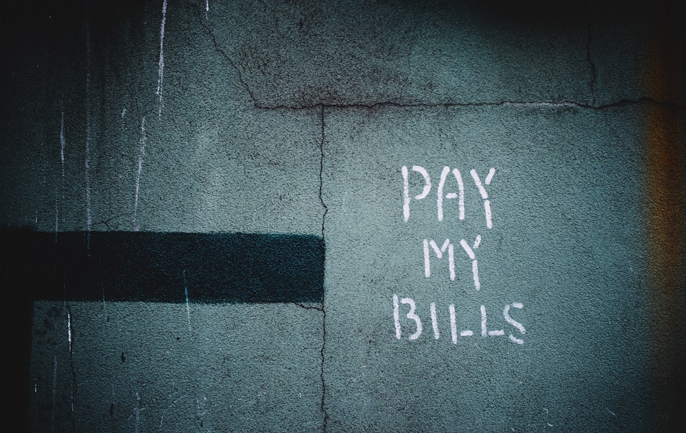 shallow focus photo of wall with pay my bills paint