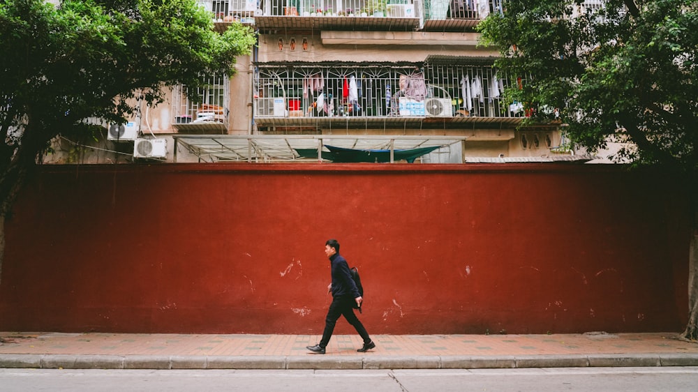 man wearing black jacket walking on pathway near buildings