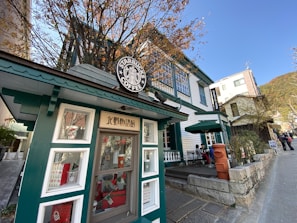 A bustling coffee shop storefront framed by colorful autumn leaves in a Denver neighborhood.