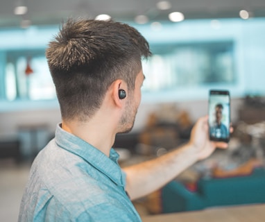 shallow focus photo of man in gray collared top taking selfie