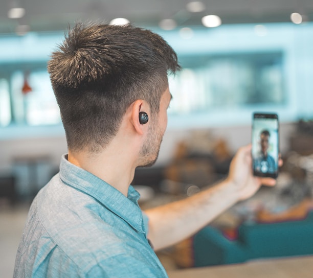 shallow focus photo of man in gray collared top taking selfie