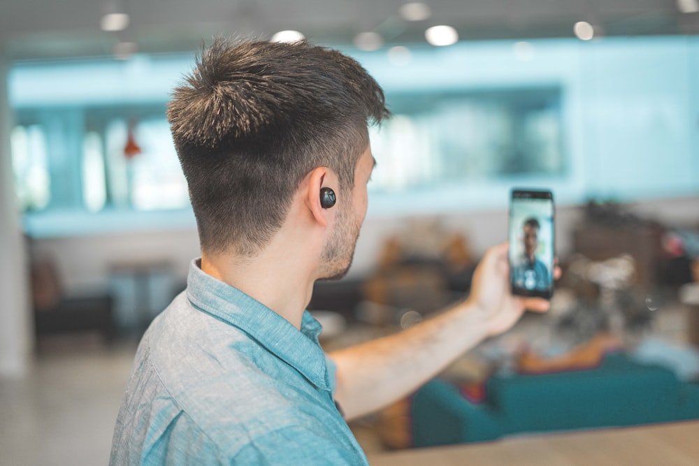 shallow focus photo of man in gray collared top taking selfie