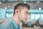 man wearing blue dress shirt with black Bluetooth earbuds