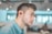 man wearing blue dress shirt with black Bluetooth earbuds