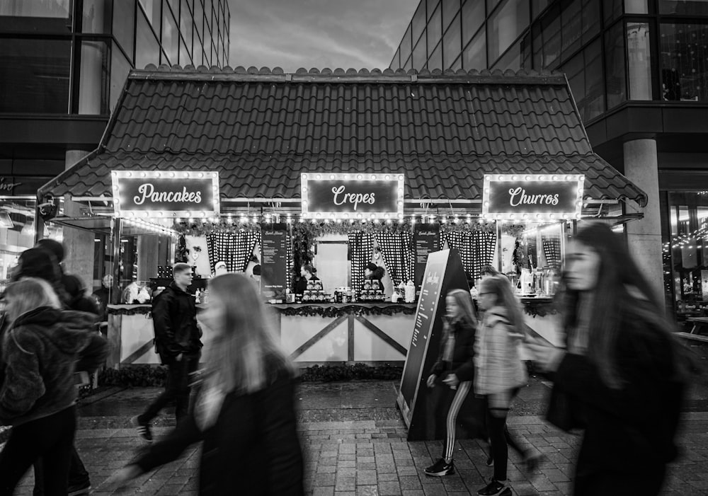 grayscale photography of walking people beside stall