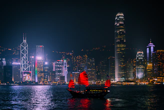 A traditional junk boat with red sails on Victoria Harbour in Hong Kong at night