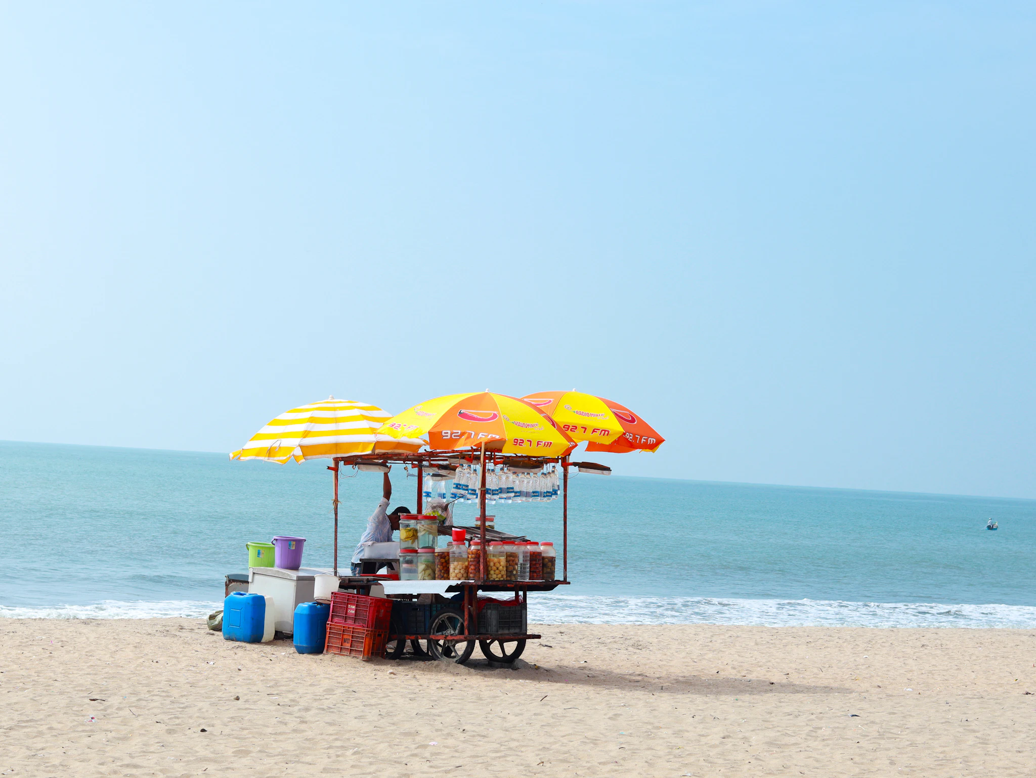 A snack stall under bright umbrellas on Kozhikode beach