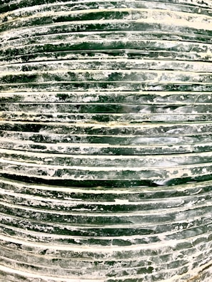 A close-up view of a stack of dark green tires covered in white dust or residue. The horizontal lines formed by the stacked tires create a pattern, and the surface texture appears rough and uneven.