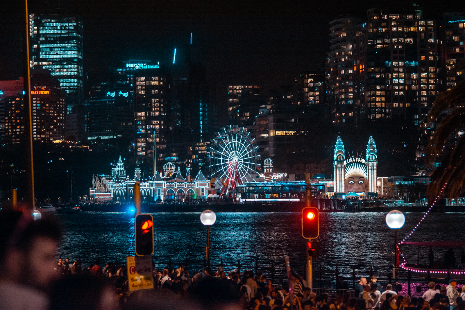 Luna Park Sydney lit up at night with the ferris wheel and the Harbour Bridge overhead