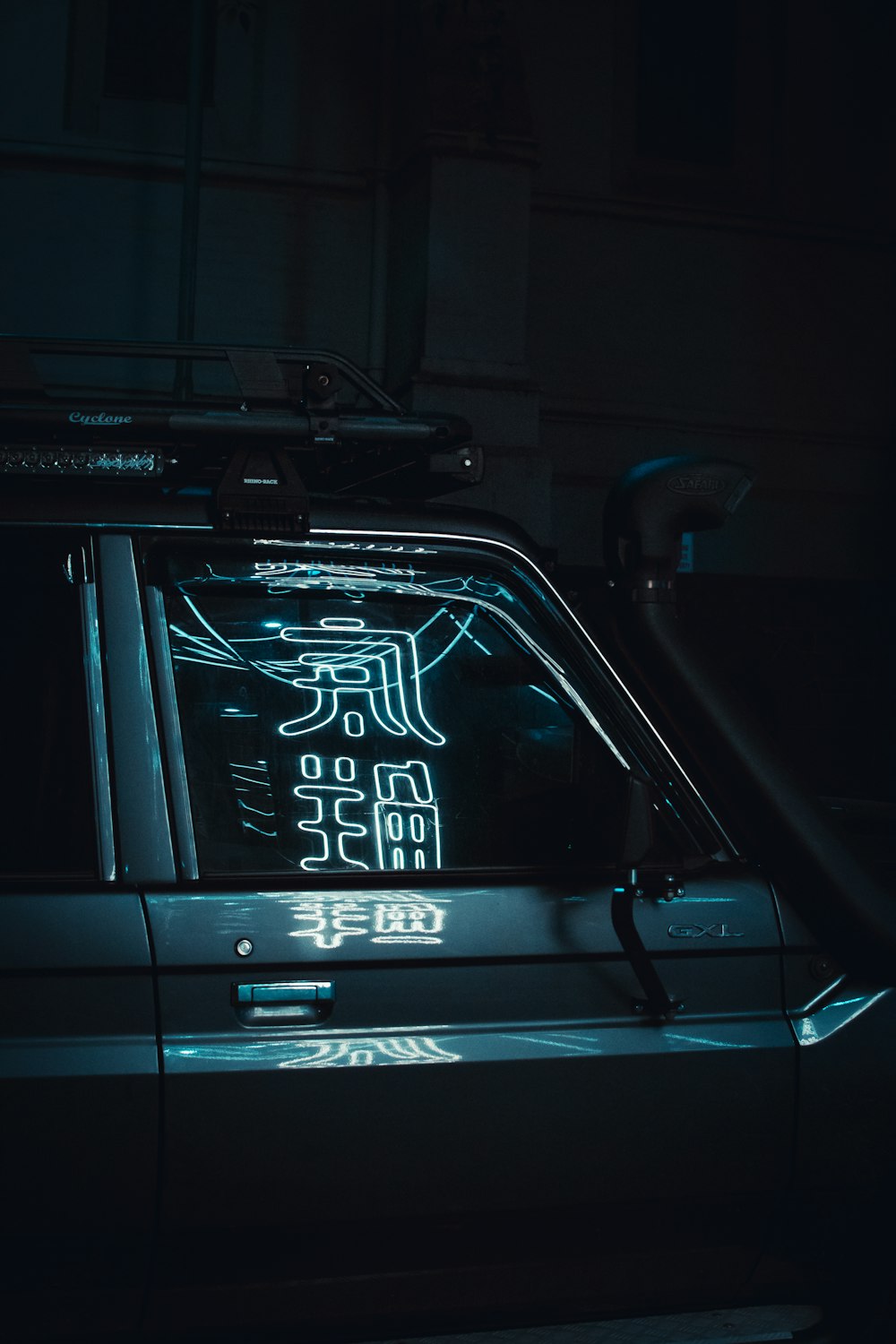 parked car with kanji signage reflecting on it